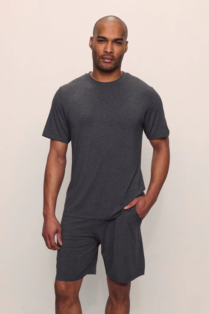 Man wearing a dark gray t-shirt and shorts pajama set on a plain background