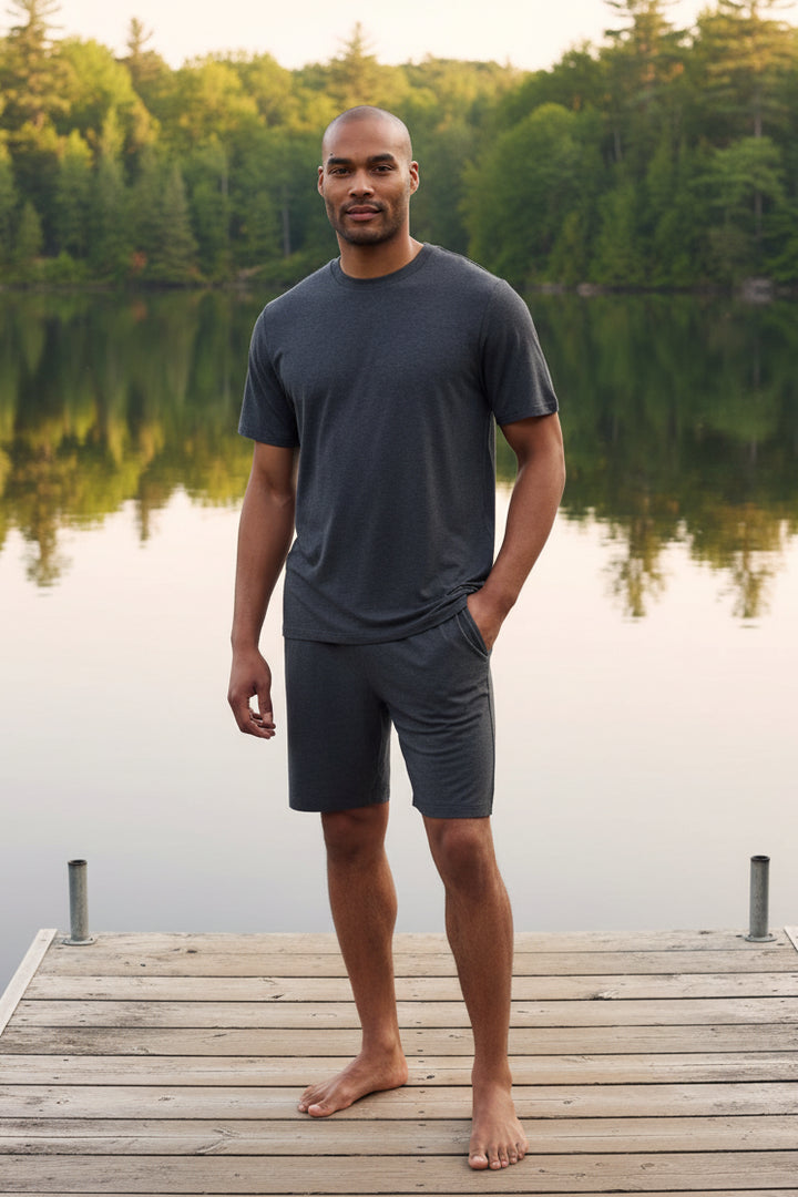 Man wearing a dark gray t-shirt and shorts mens pajama set on a plain background