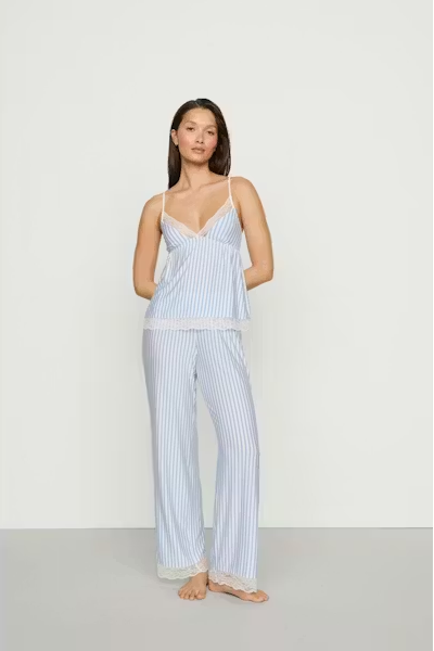Woman wearing a light blue striped pajama set on a white background