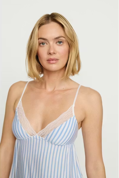 Woman wearing a blue and white striped camisole with lace details on a plain background