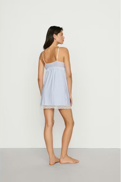 Woman wearing a light blue striped nightgown against a white background
