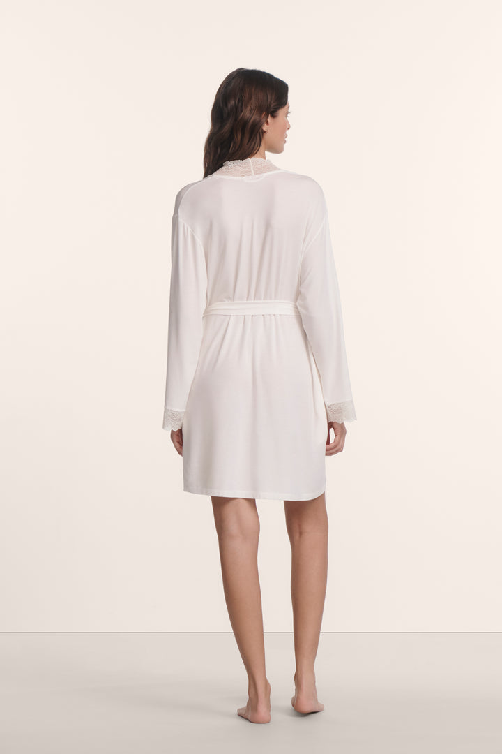 Woman wearing a white dressing gown against a plain background