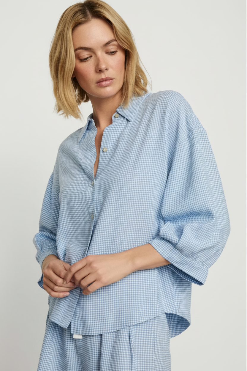Woman wearing a blue checkered shirt and pants on a plain background