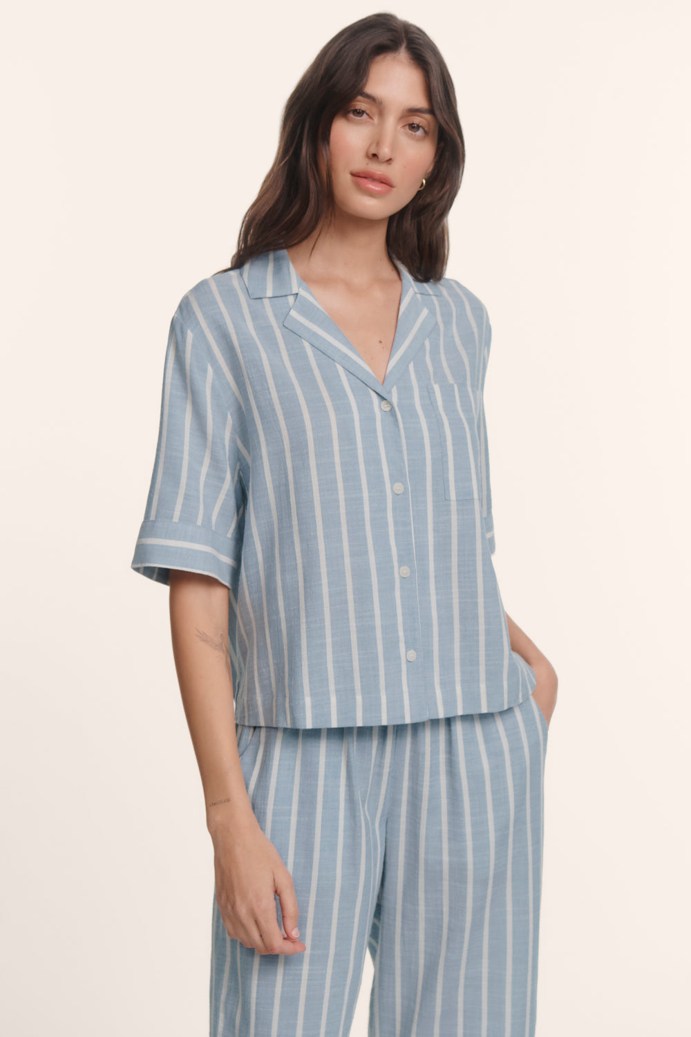 Woman wearing an eberjey blue and white striped nautico pajama set. Short sleeve boxy top and wide leg pants.