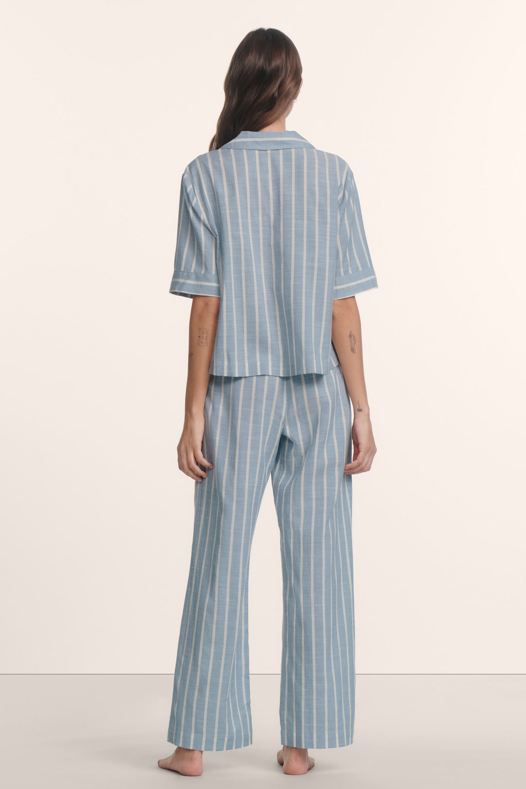 Woman wearing an eberjey blue and white striped nautico pajama set. Short sleeve boxy top and wide leg pants.