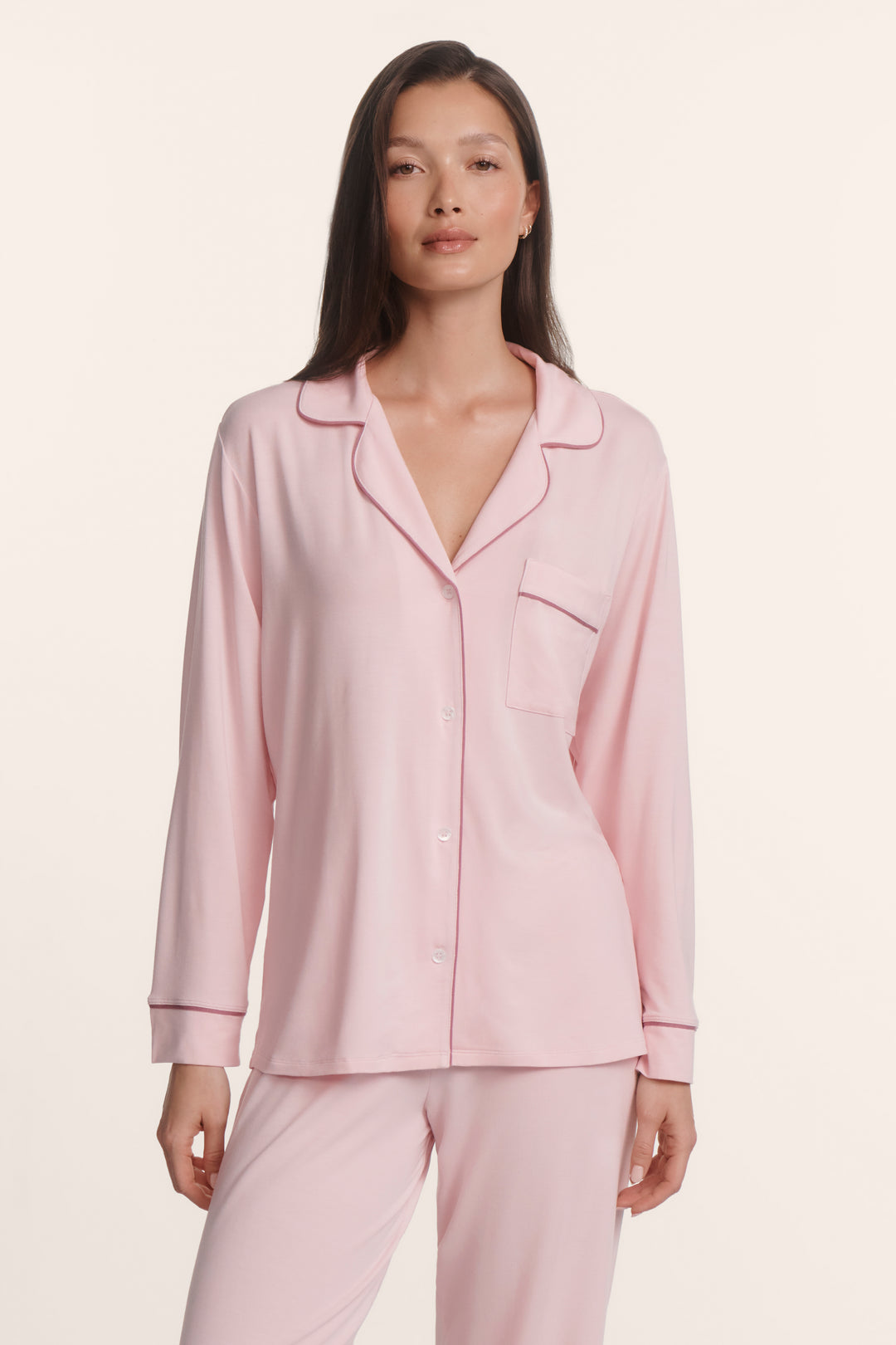 Woman wearing a pink soft modal pajama set against a white background