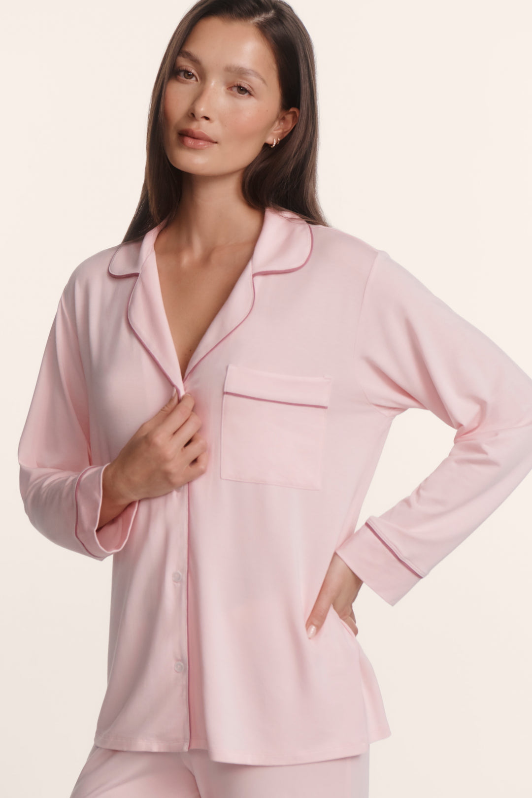 Woman wearing a light pink pajama set on a plain background