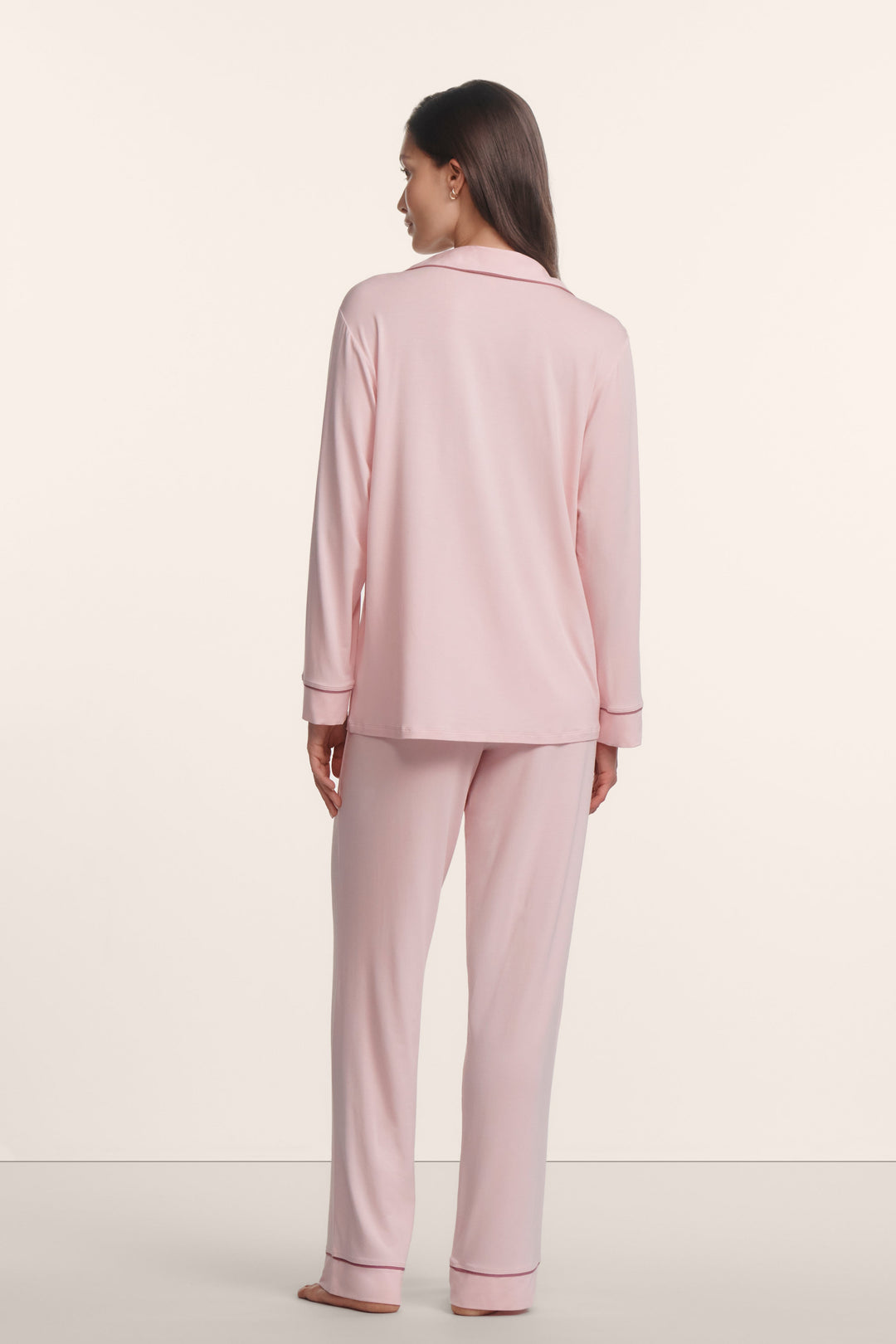 Woman wearing a light pink pajama set against a white background