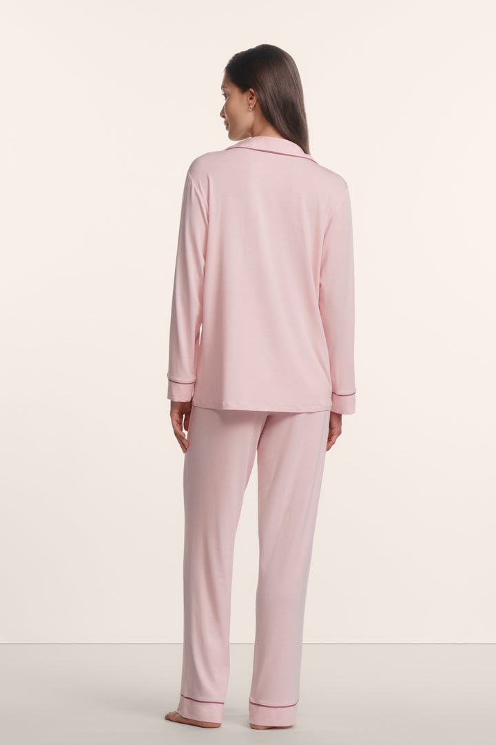 Woman wearing a light pink pajama set against a white background