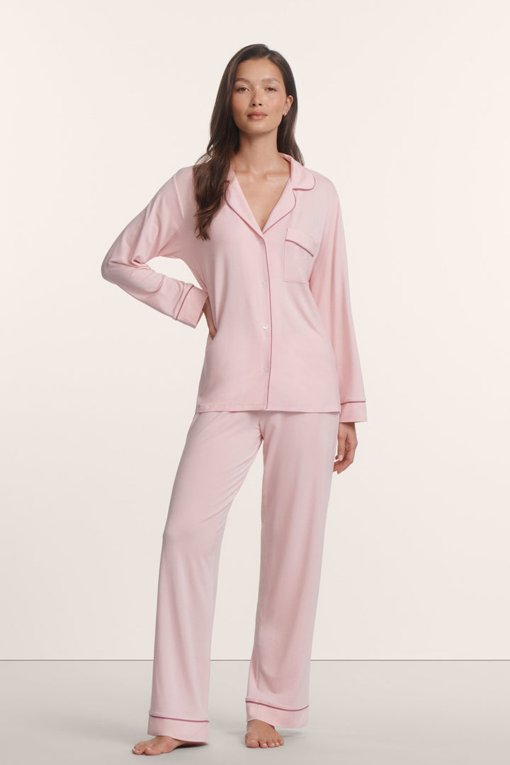 Woman wearing a pink pajama set against a white background