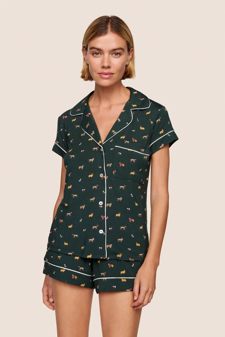 Woman wearing a dark green pajama set with animal pattern on a beige background