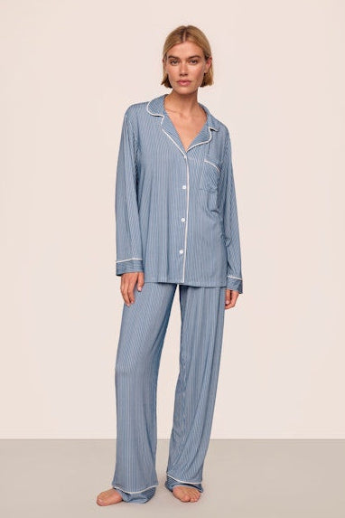 Woman wearing a blue striped pajama set against a beige background