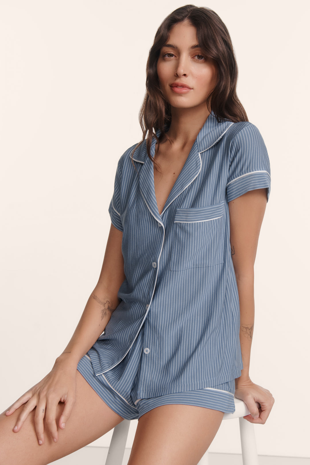 Woman wearing a blue striped pajama set on a beige background