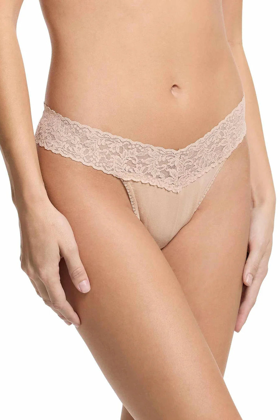 Beige lace thong worn by a person on a white background