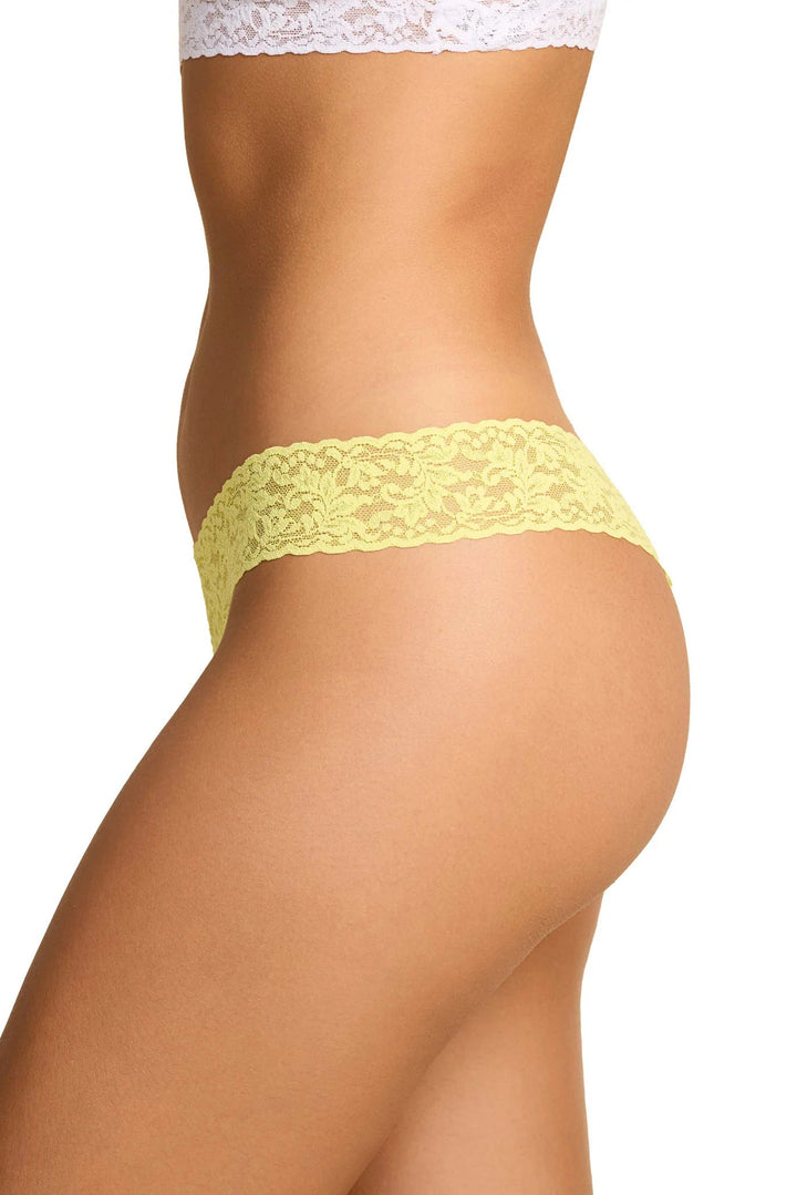 Yellow lace thong worn by a person on a white background