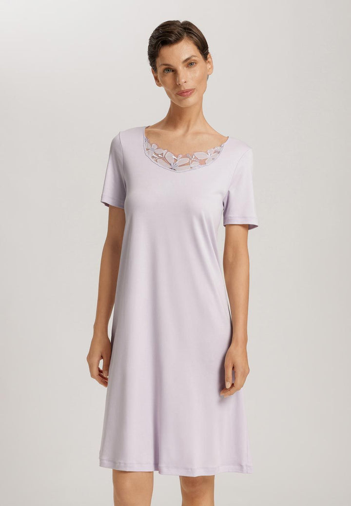 Woman wearing a light purple nightgown with lace trim on a plain background