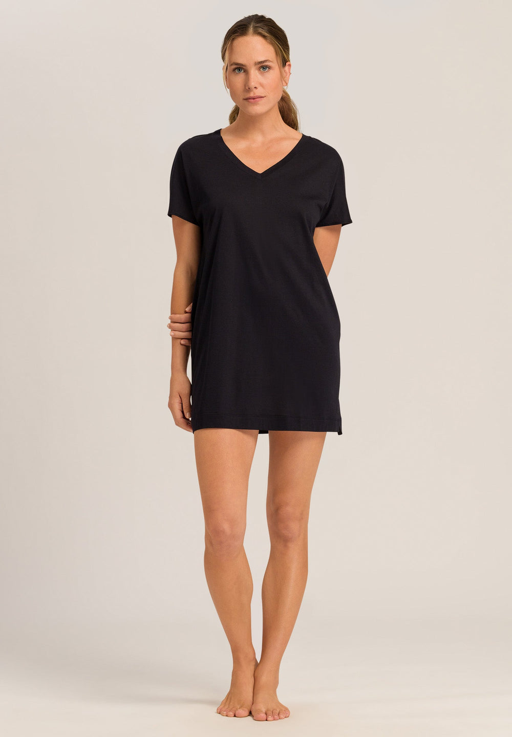 Woman wearing a black t-shirt nightdress on a plain background