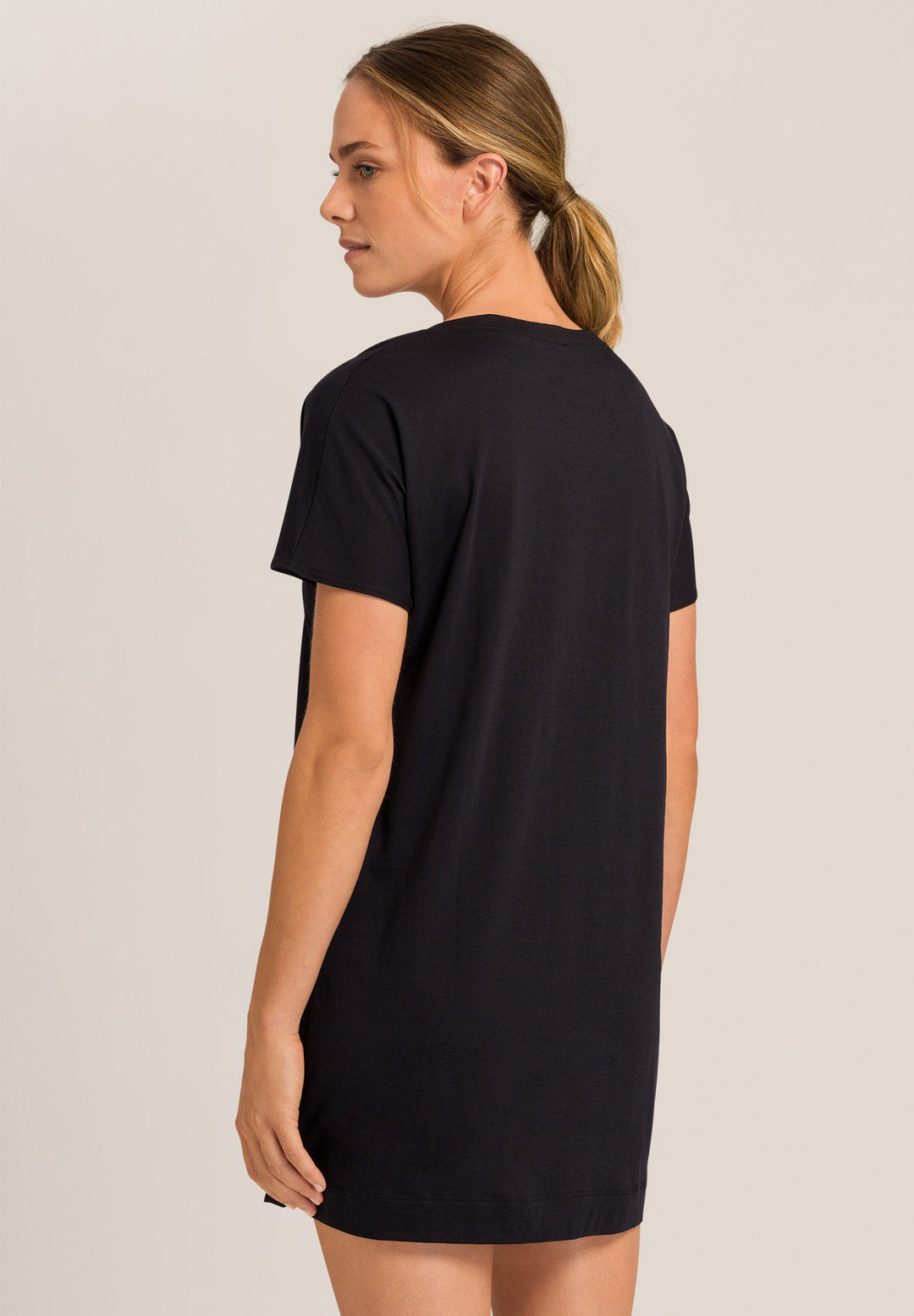 Woman wearing a black t-shirt nightgown against a plain background