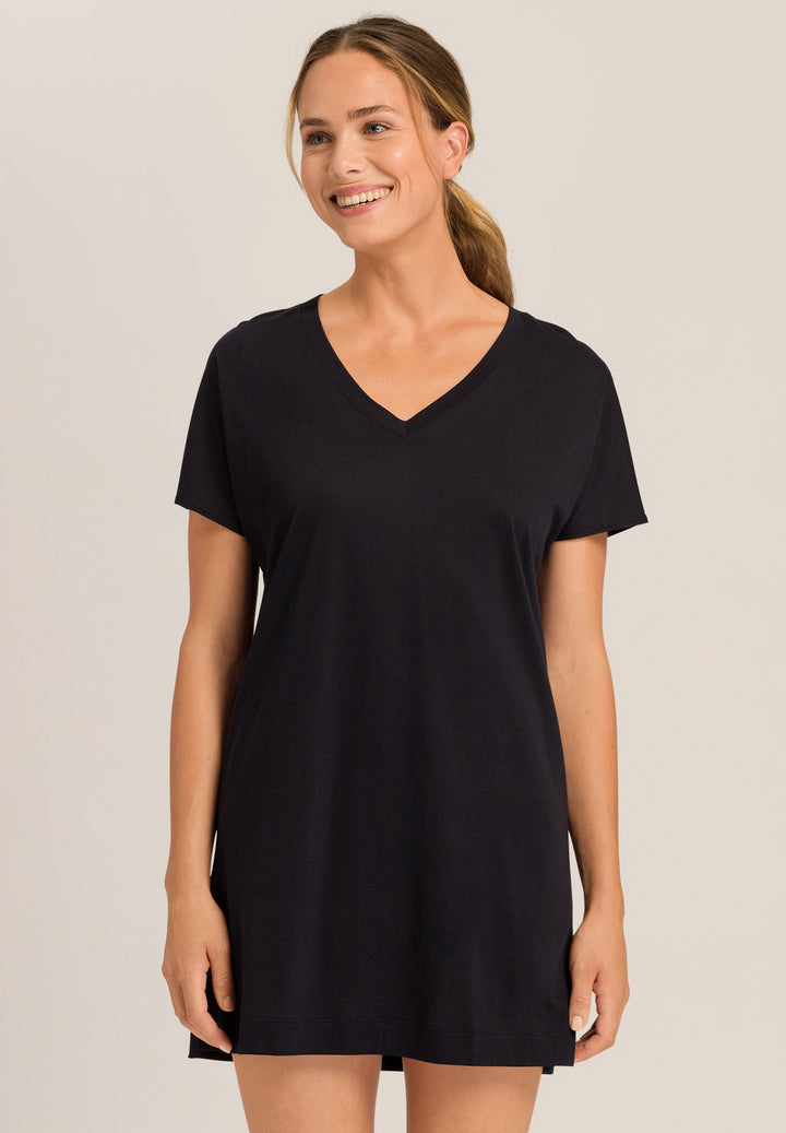 Woman wearing a black V-neck nightdress against a plain background