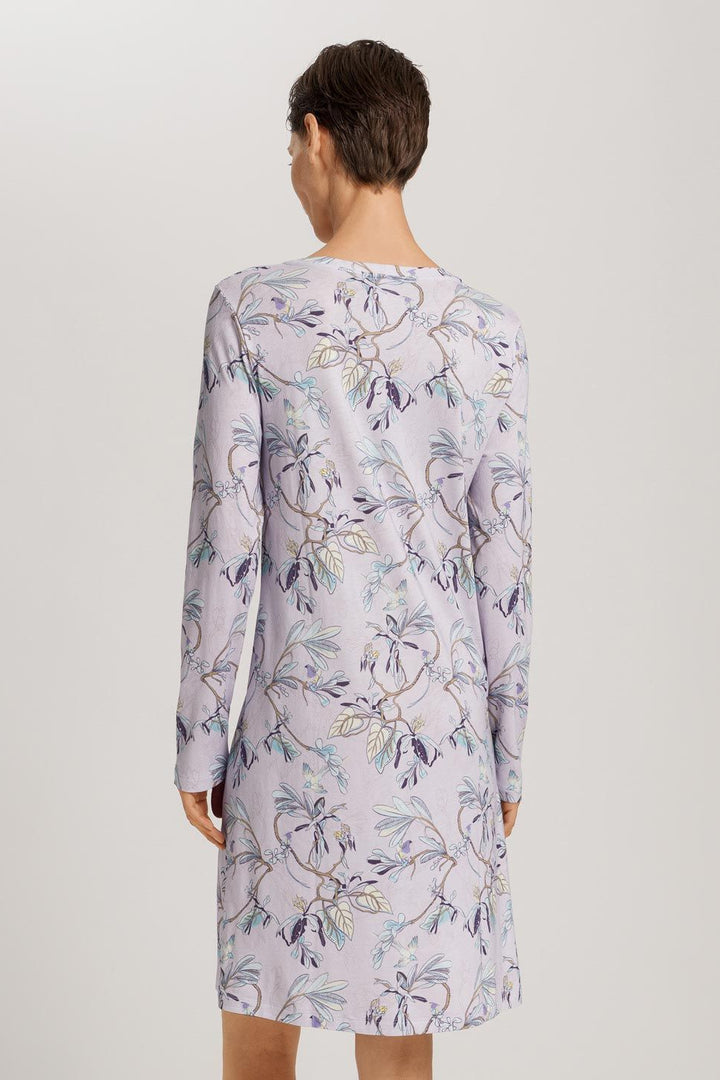 Woman wearing a floral dress with long sleeves on a plain background