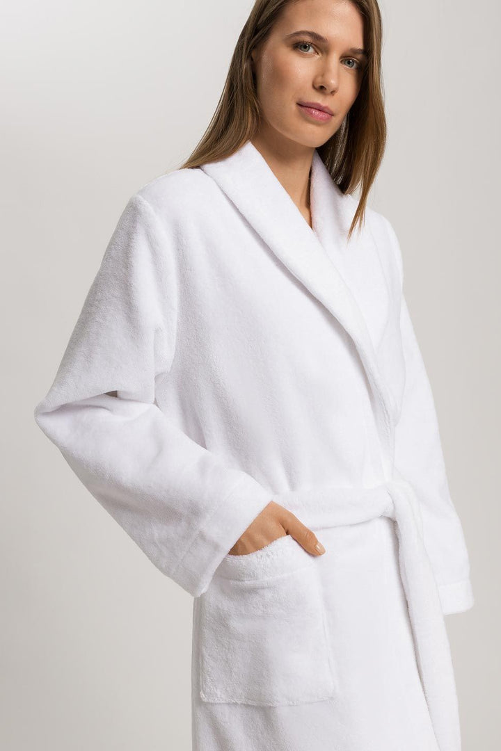 Woman wearing a white robe against a plain background