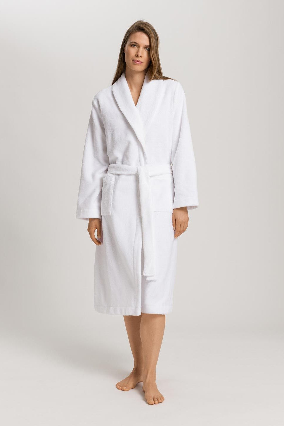 Woman wearing a white bathrobe on a plain background