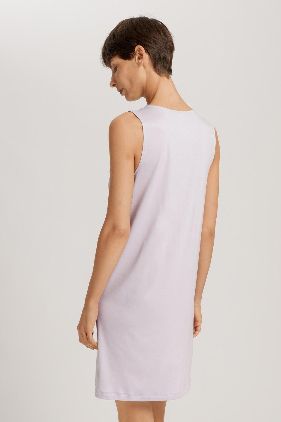Woman wearing a light purple sleeveless dress against a plain background