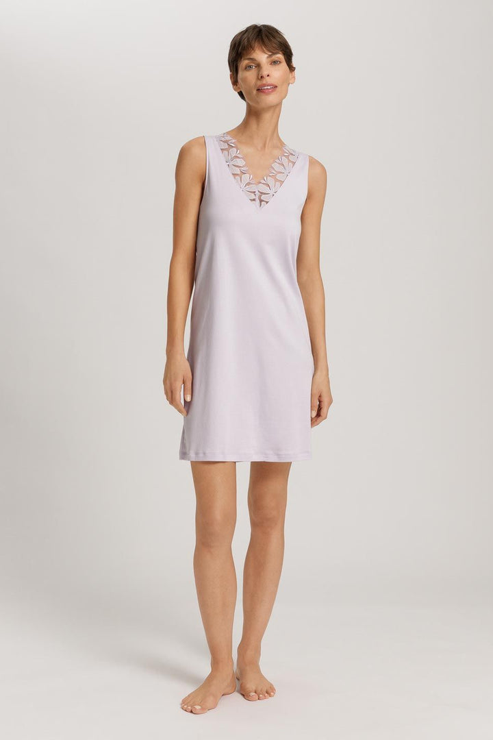 Woman wearing a light purple night dress with lace details on a white background