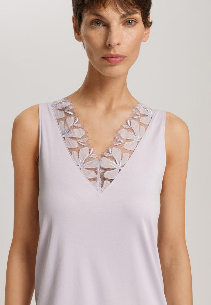 Woman wearing a light purple sleeveless nightgown with floral lace details on a plain background