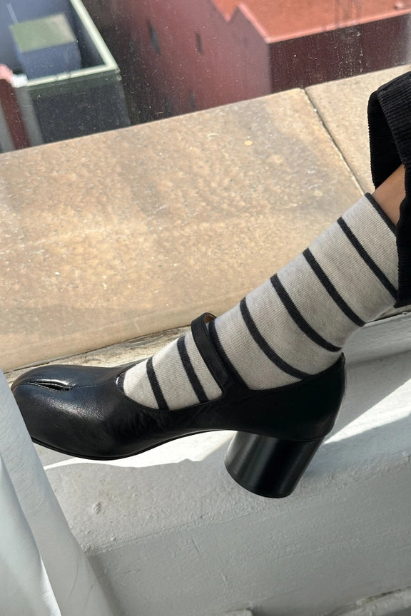 Black high-heeled shoe and striped socks on a concrete surface