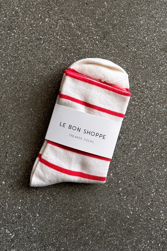 White sock with red stripes and 'Le Bon Shoppe' label on a gray surface
