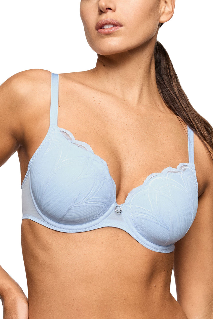A woman wearing a light blue underwire bra with scalloped lace trim and a small silver button at the center, shown against a plain white background.