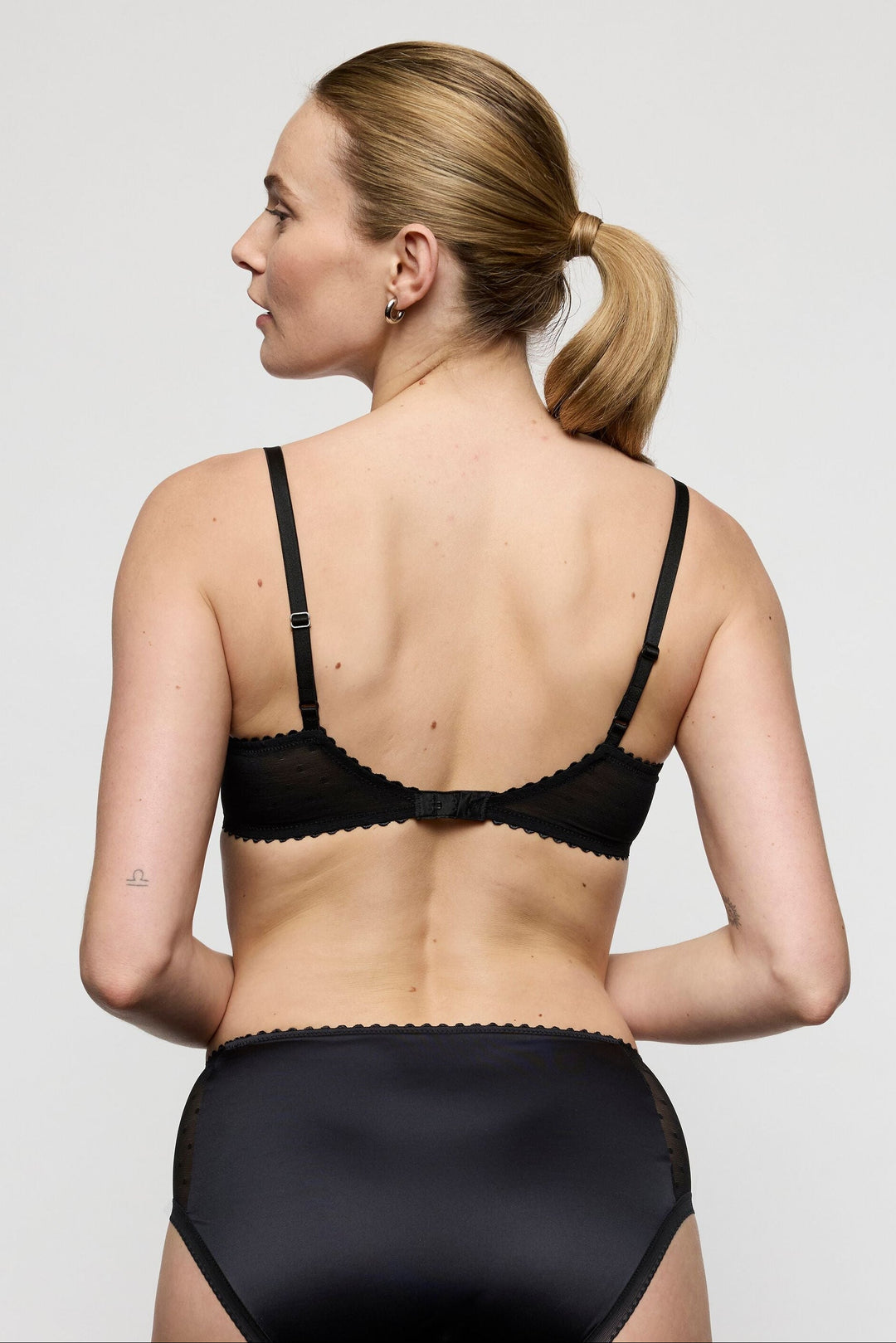 woman wearing the Marie Jo Noova Half Padded Balcony Bra with the matching full brief.  Printed bows on mesh lace with pink floral edges and half padded. Comfortable and gorgeous set with sexy boudoir look. 