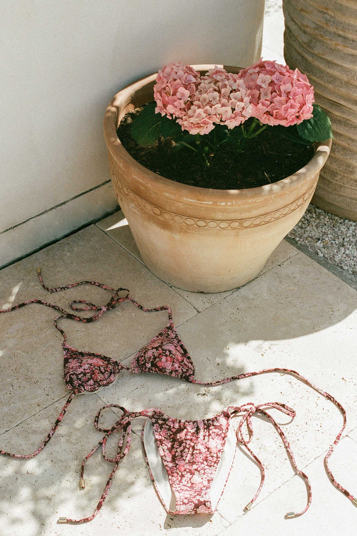 Pink sequin bikini on a stone surface with a potted plant in the background