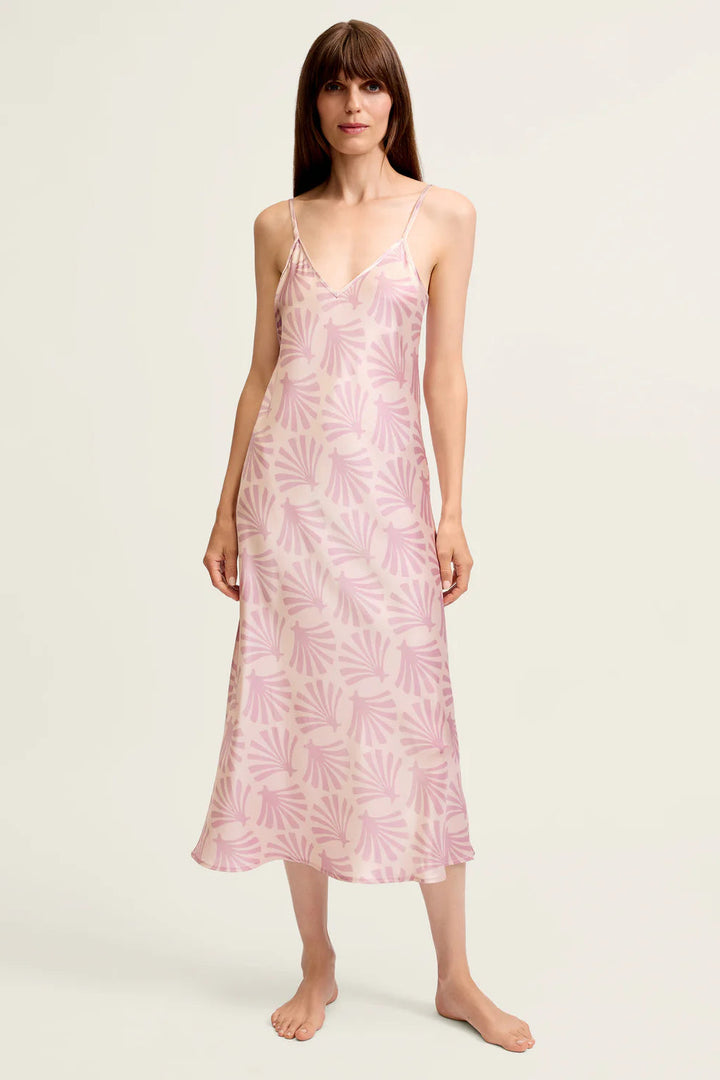 Woman wearing a pink floral silk slip dress on a white background