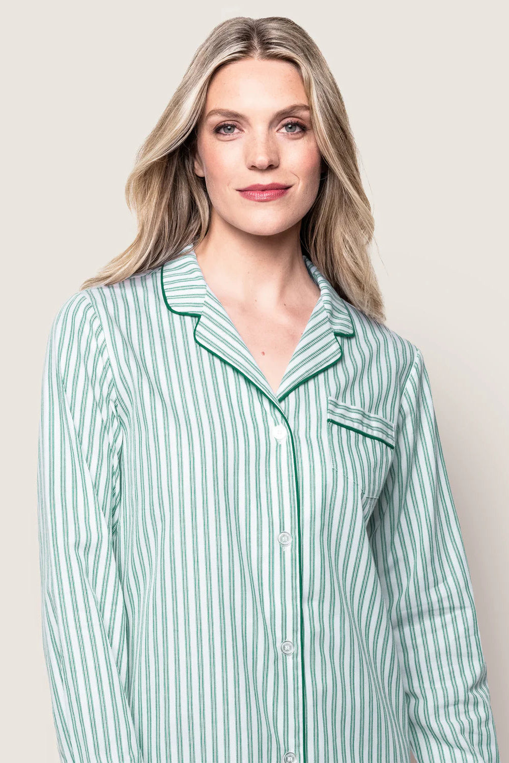 Woman wearing a green and white striped pajama top against a plain background