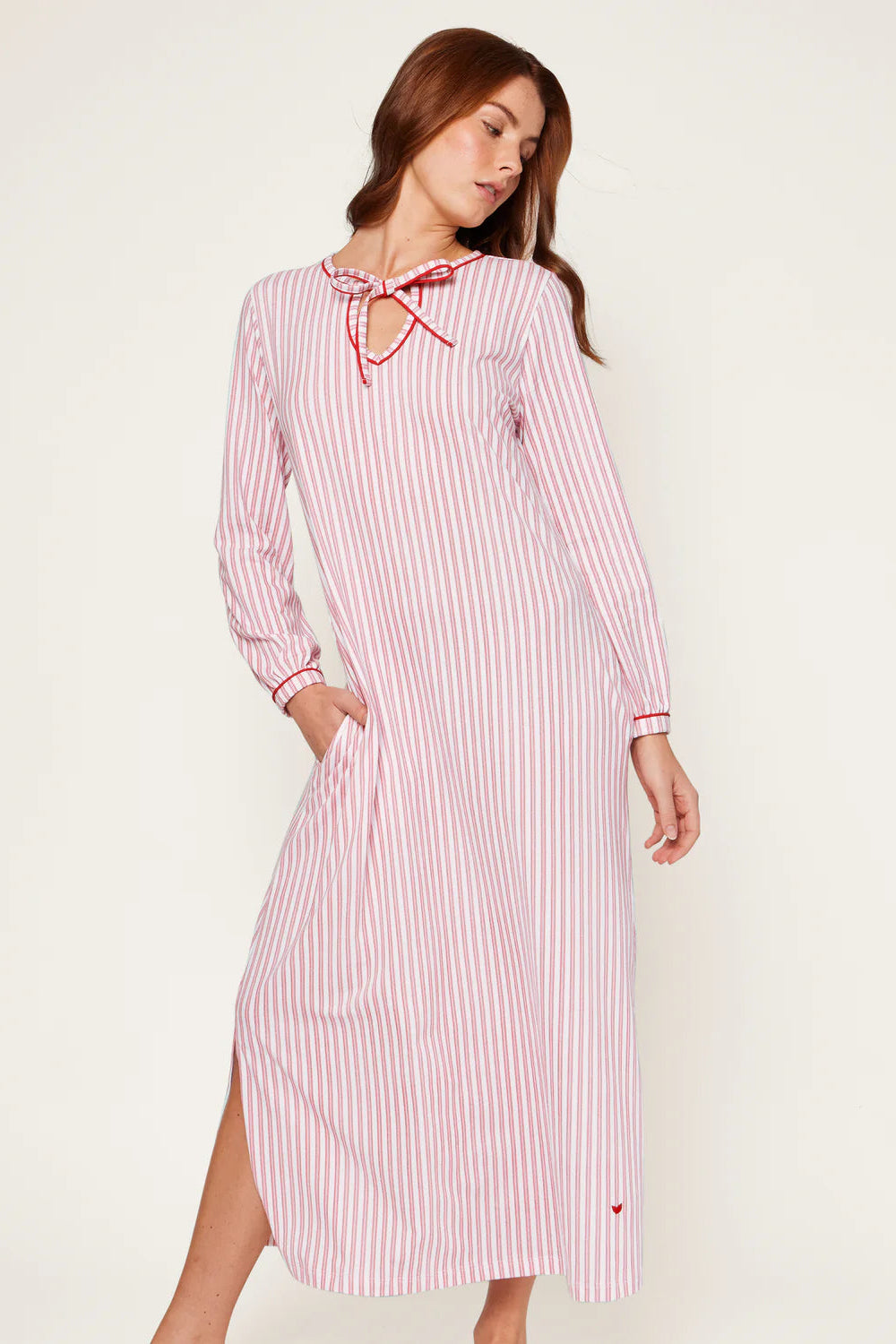 Woman wearing a pink and white striped dress with a bow neckline on a white background