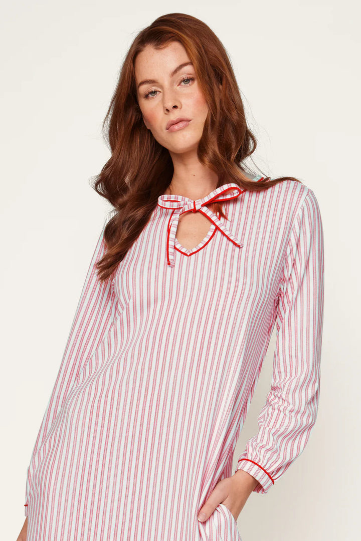 Woman wearing a red and white striped dress with a bow neckline on a light background