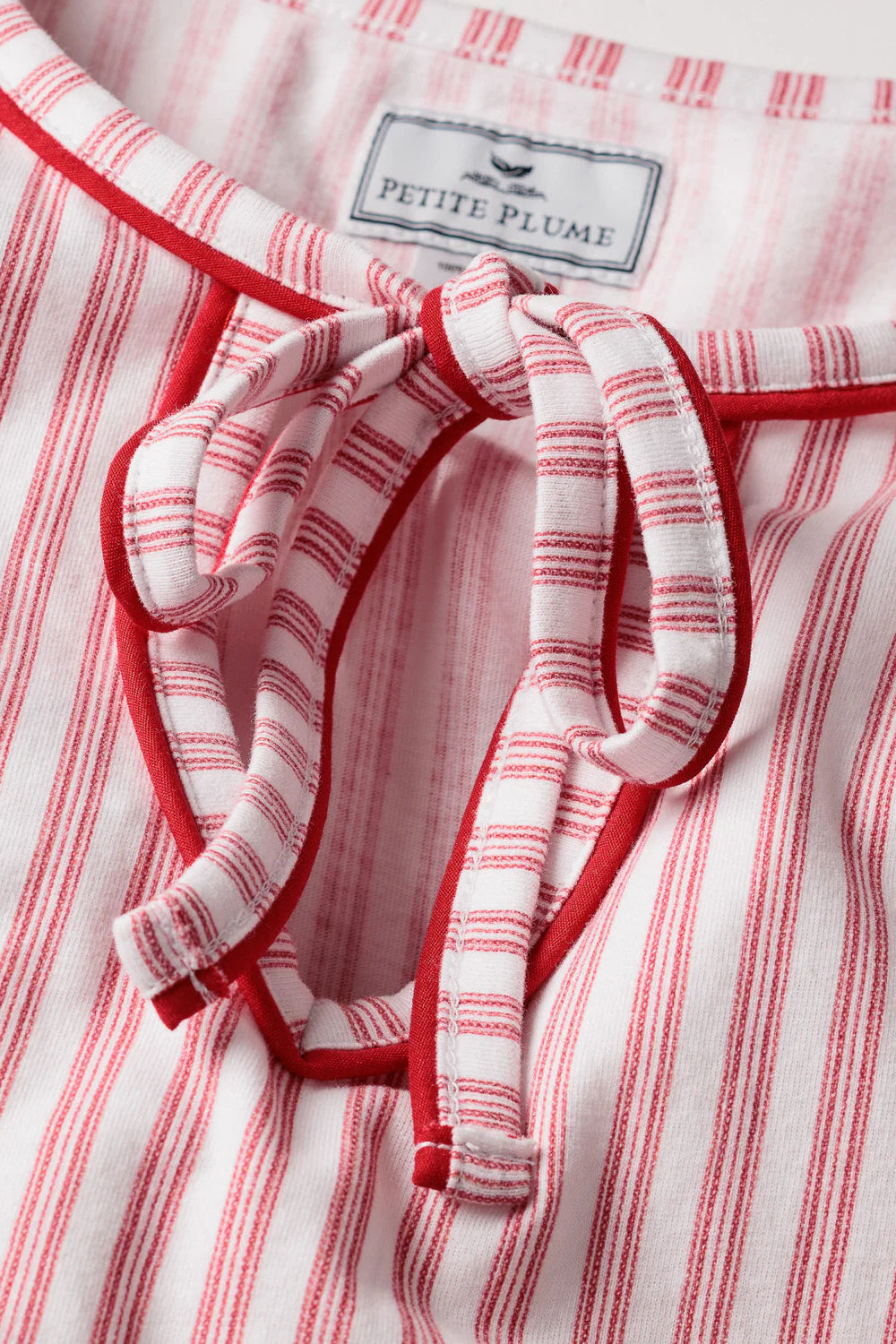 Red and white striped garment with a bow detail and 'Petite Plume' label.