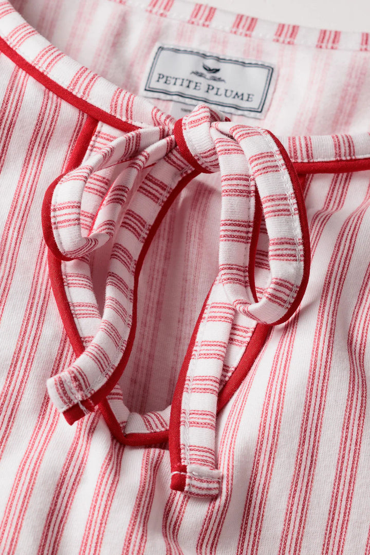 Red and white striped garment with a bow detail and 'Petite Plume' label.