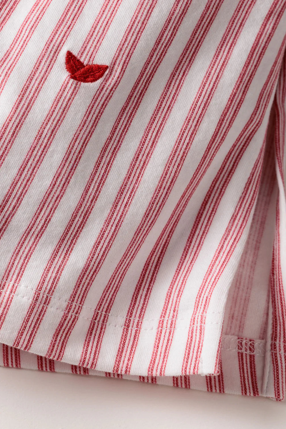 Red and white striped fabric with a small embroidered design on a light background