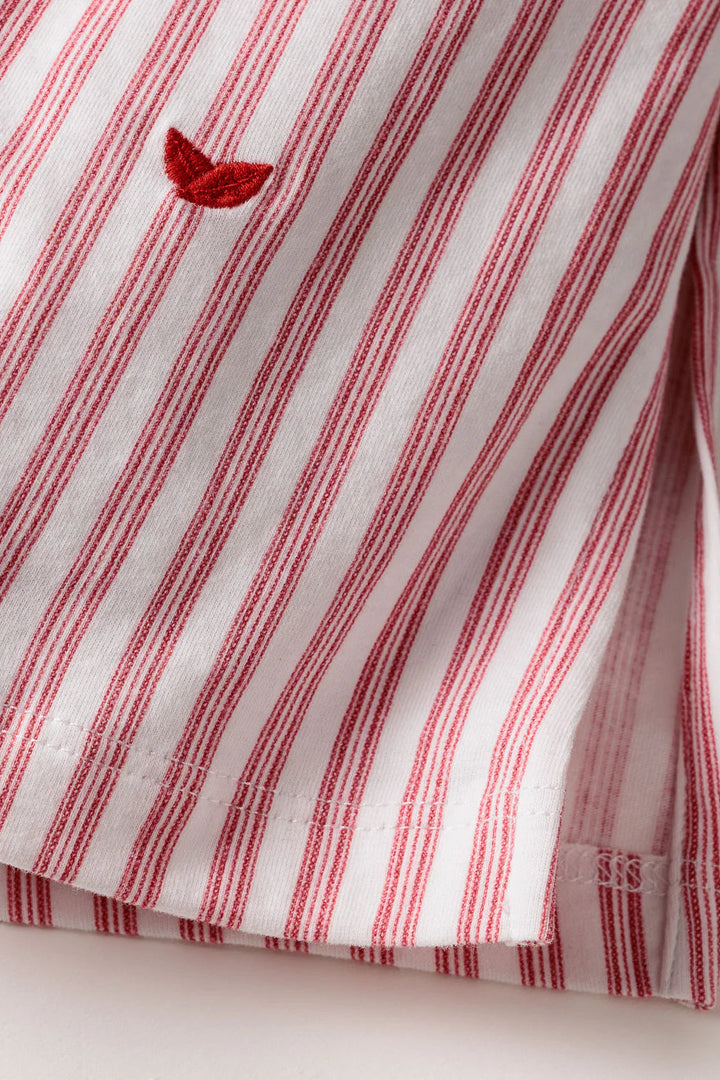 Red and white striped fabric with a small embroidered design on a light background