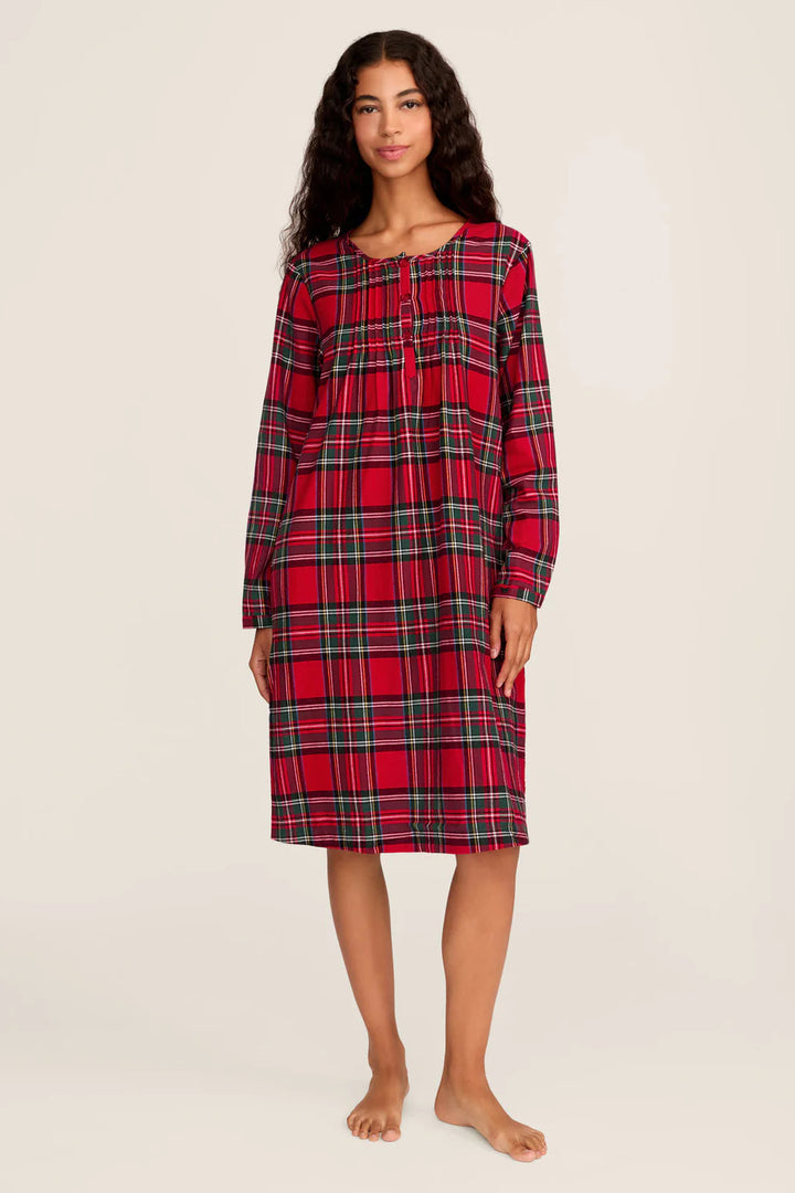 Woman wearing a red plaid nightshirt on a plain background
