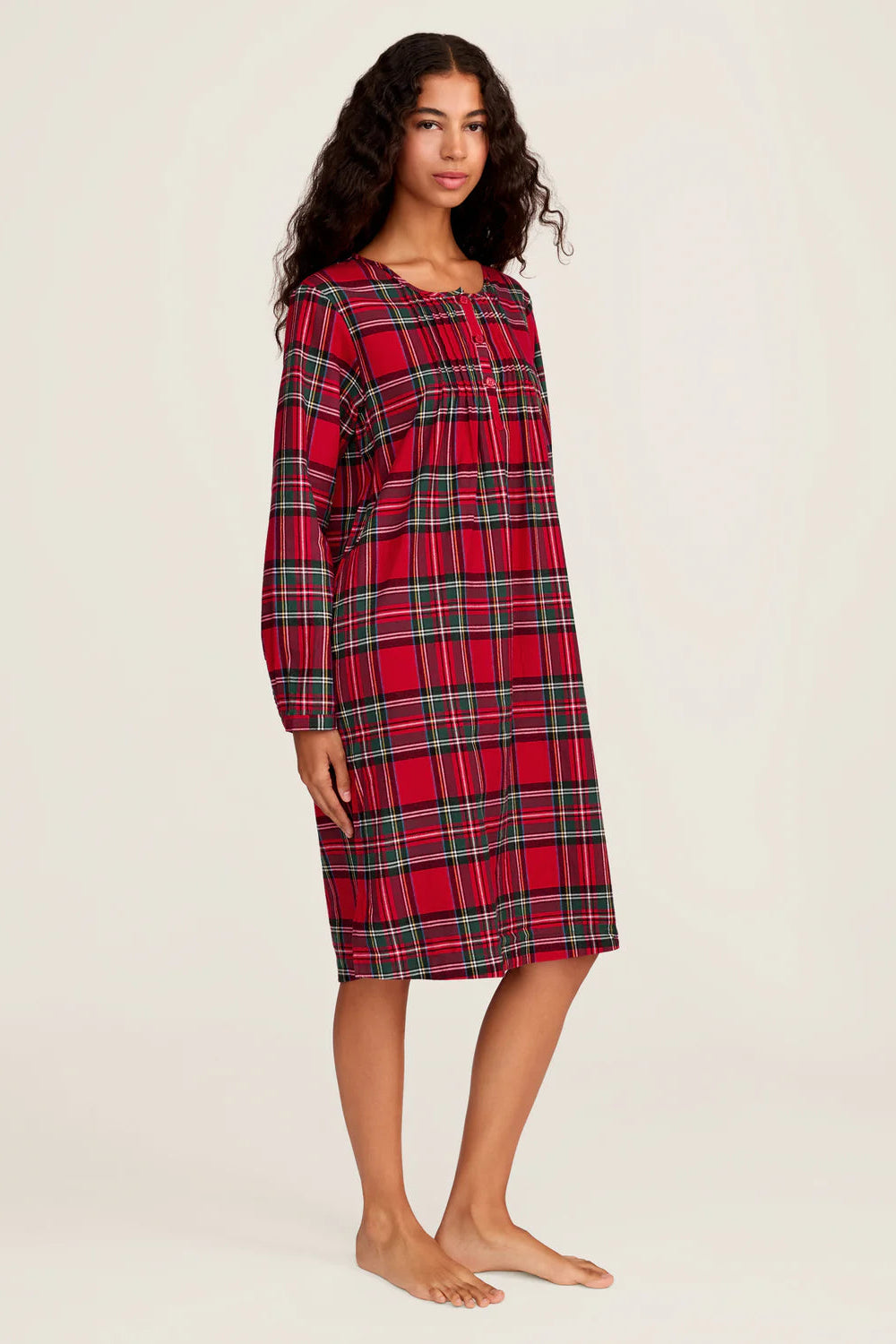 Woman wearing a red plaid nightshirt on a plain background