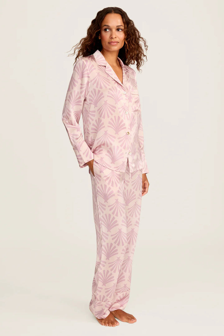 Woman wearing pink pajama set with leaf pattern on a white background