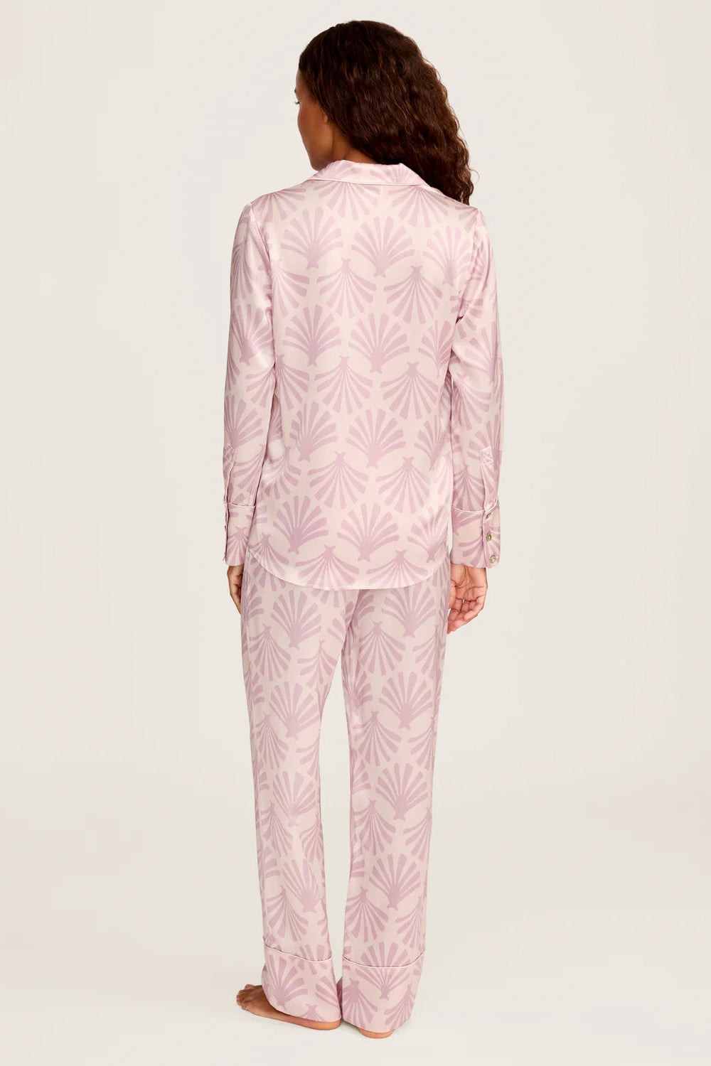 Person wearing pink pajama set with leaf pattern on a white background