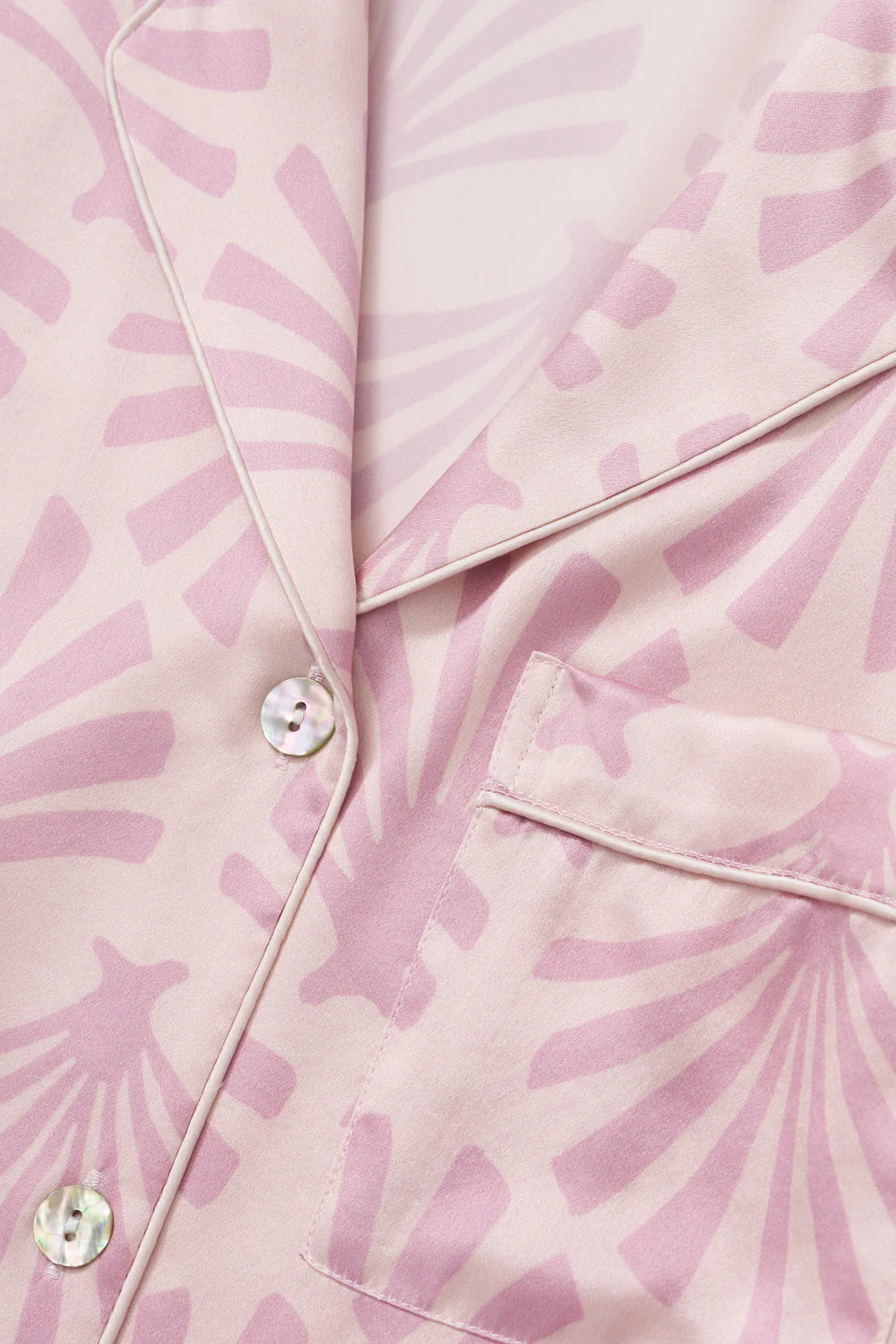 Close-up of a pink silk satin fabric with a subtle pattern and buttons.