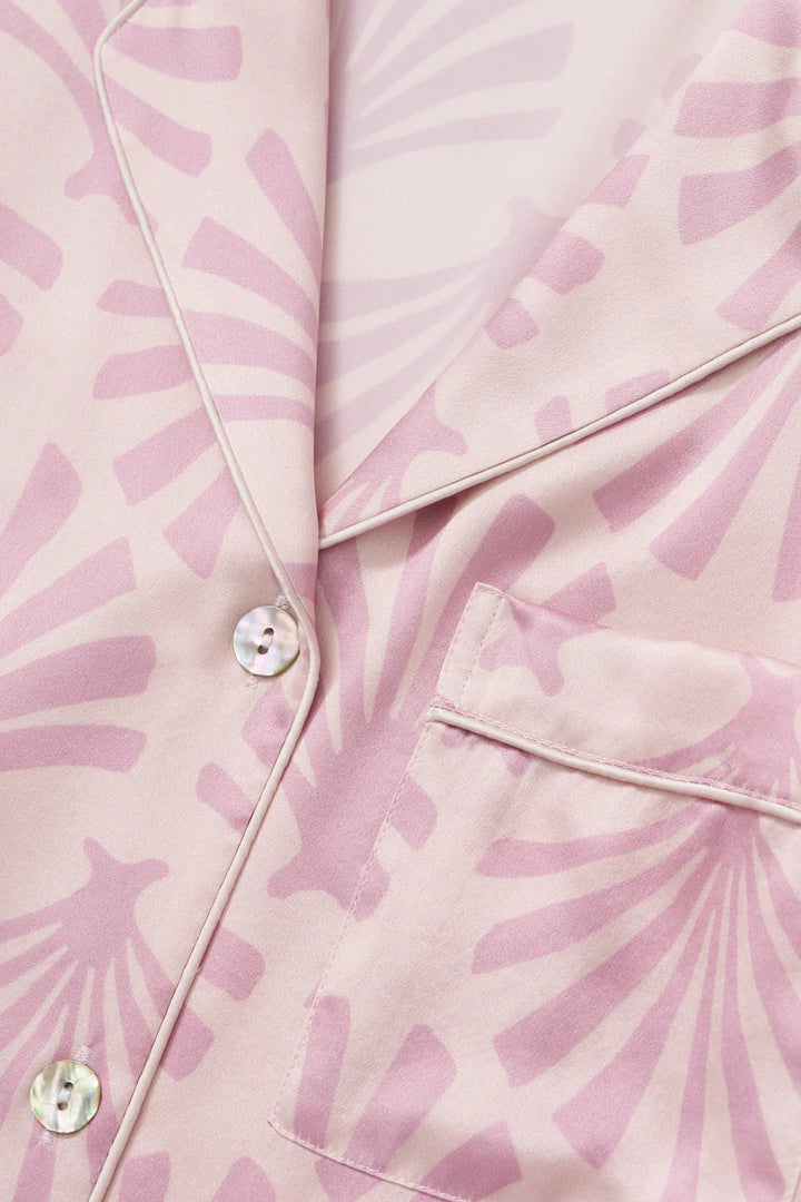 Close-up of a pink silk satin fabric with a subtle pattern and buttons.