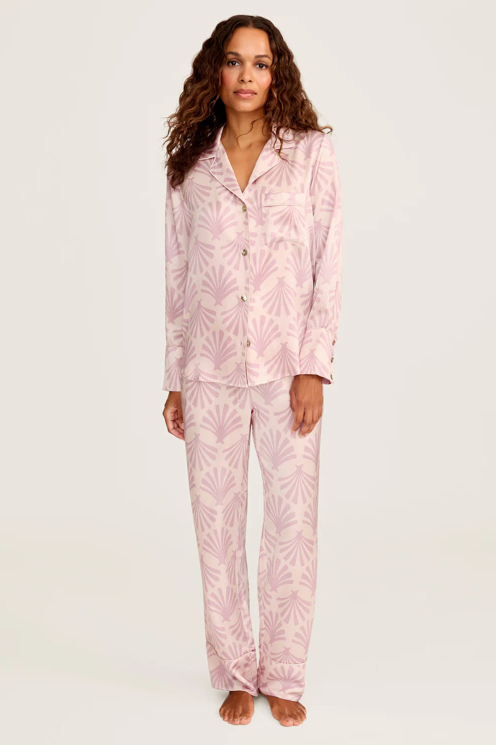 Woman wearing pink silk pajamas with a leaf pattern on a white background