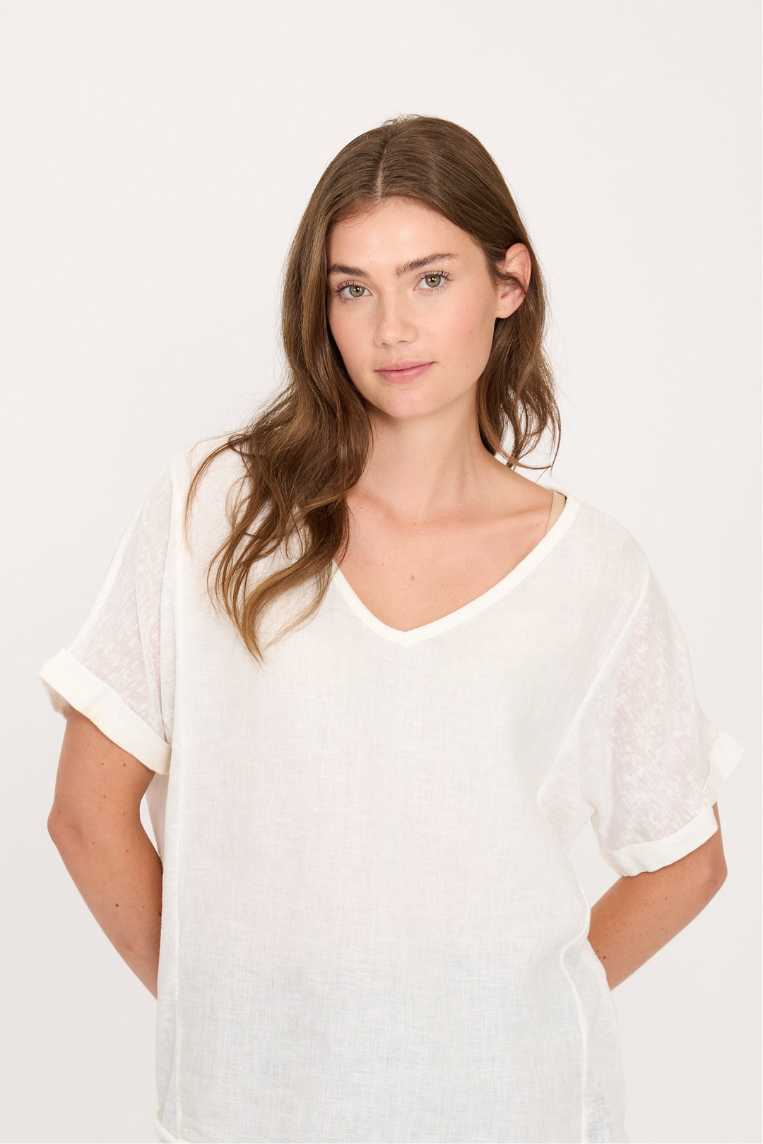 Woman wearing a white linen top and striped pants on a white background